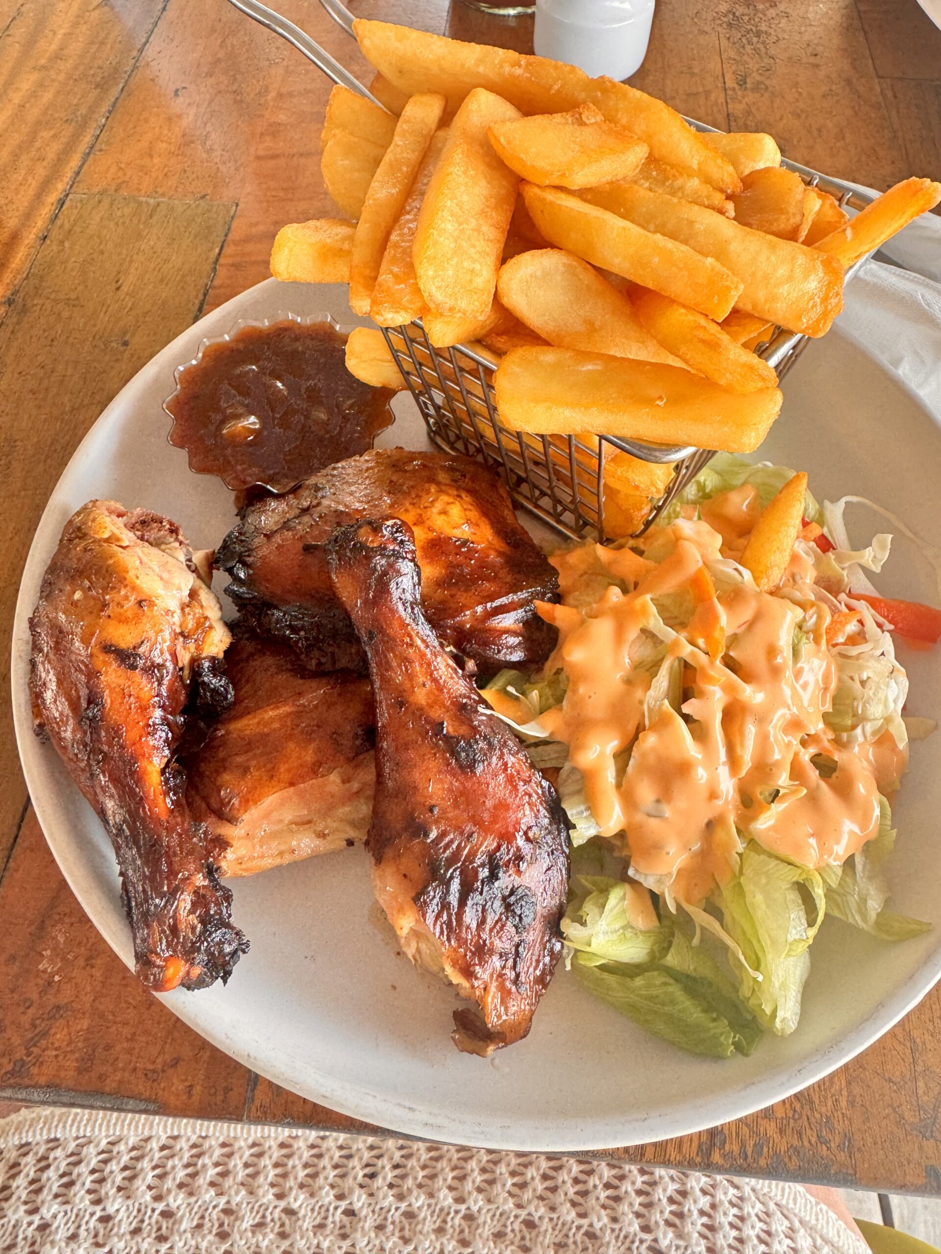 A plate of Jamaican jerk chicken with fries and slaw