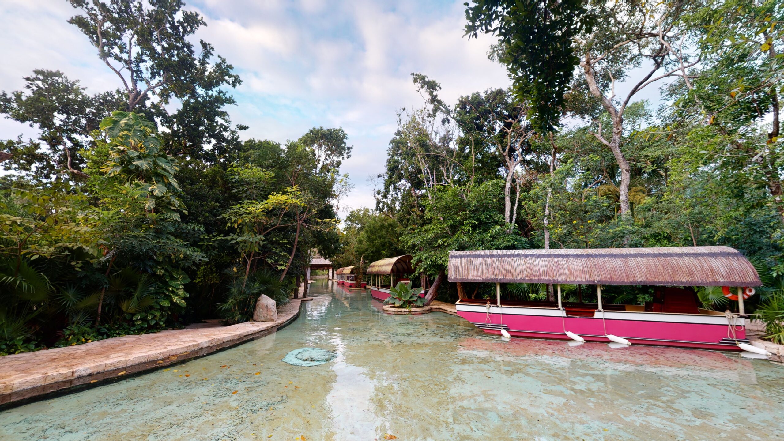 A river lined with traditional trajinera boats winding through the jungle at Hotel Xcaret México