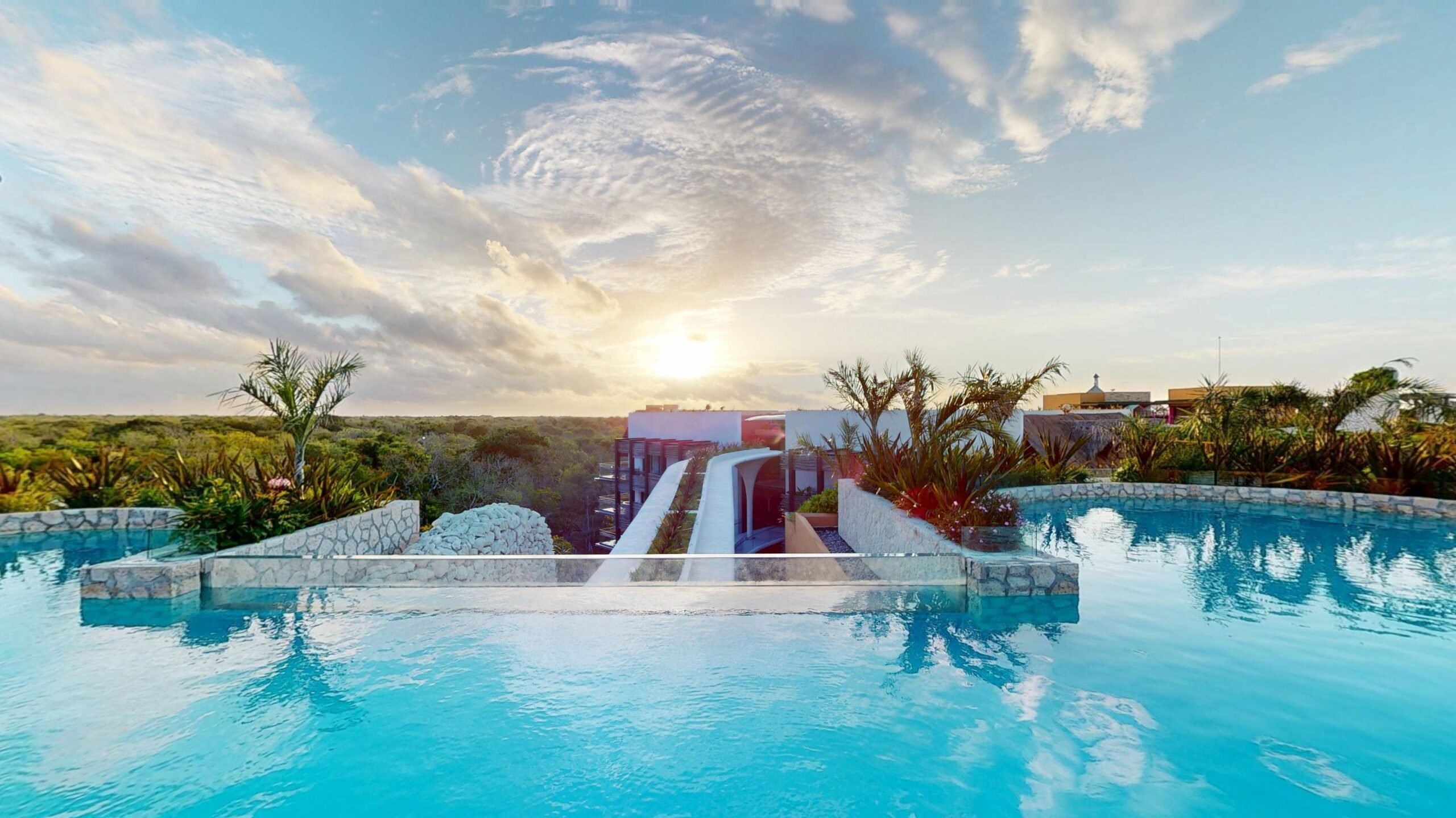 A rooftop infinity pool at sunset over the jungle at Hotel Xcaret Mรฉxico