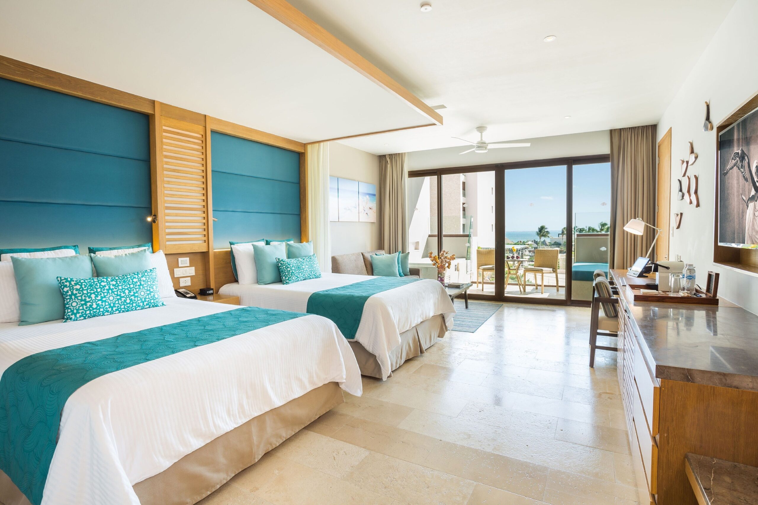 Two-bed suite with teal accents and an ocean-view balcony at Dreams Playa Mujeres
