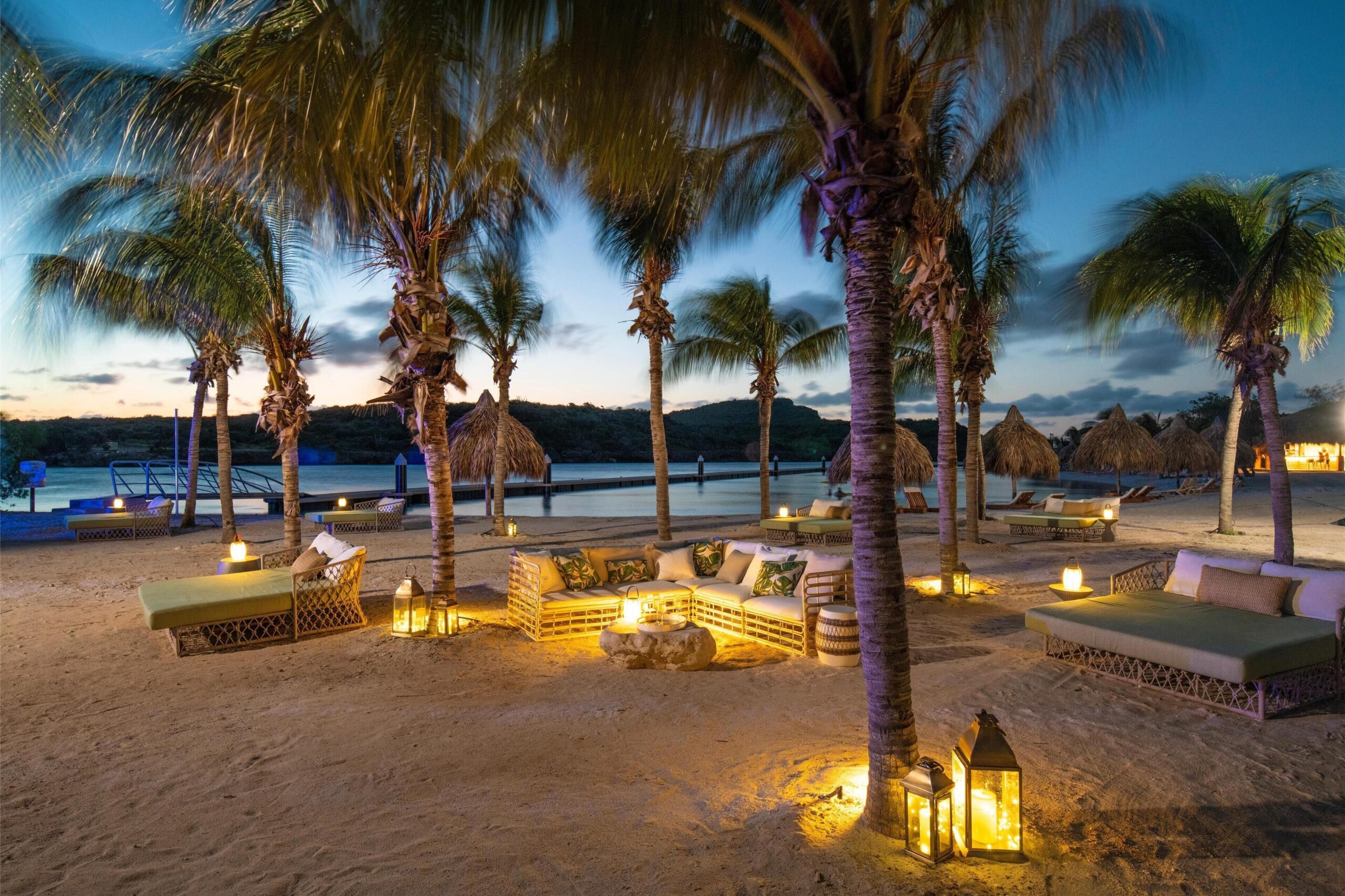 Beachfront lounge lit by lanterns at sunset at Sandals Royal Curaçao