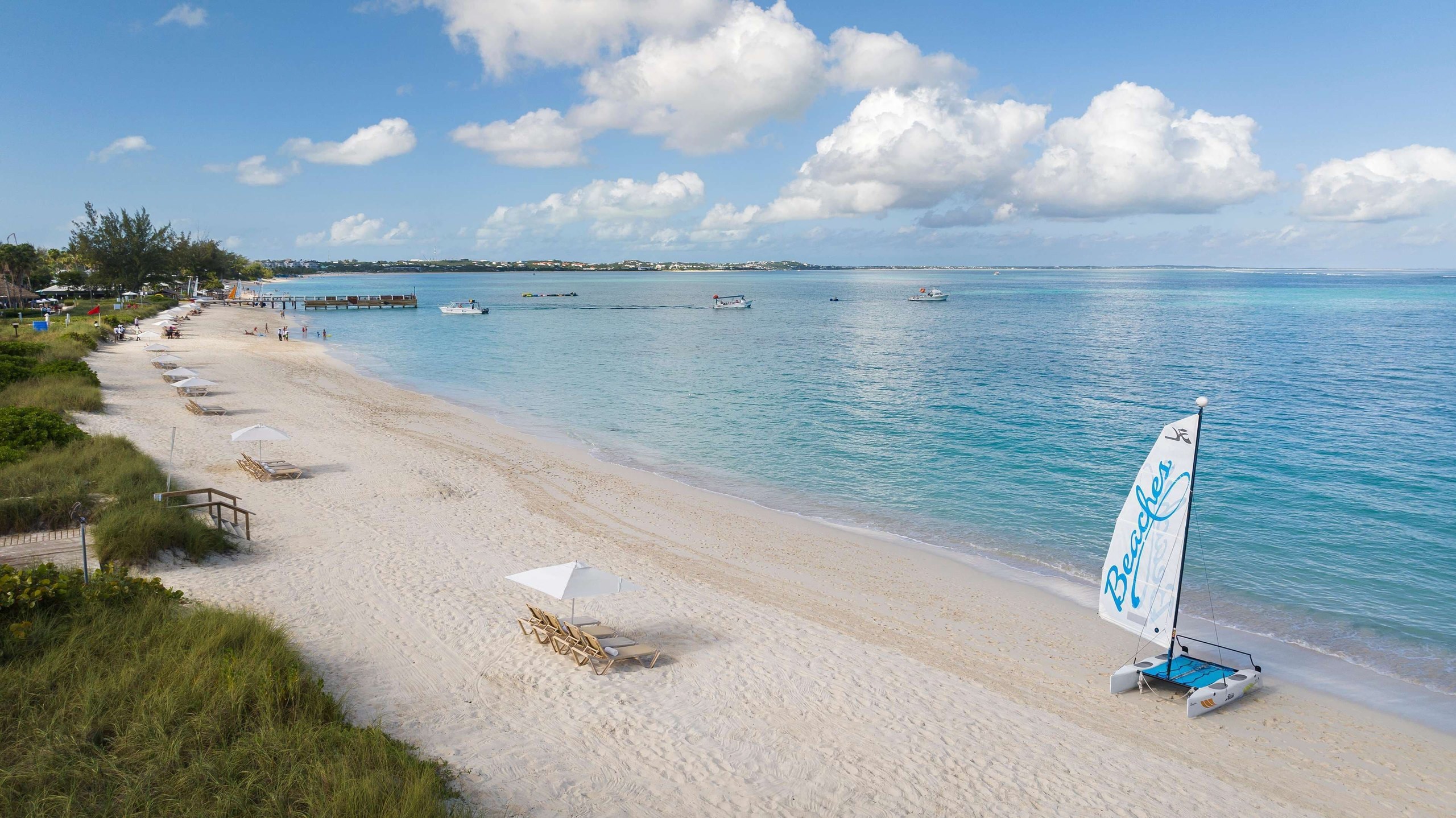 Grace Bay Beach with clear turquoise water and a wooden pier at Beaches Turks and Caicos