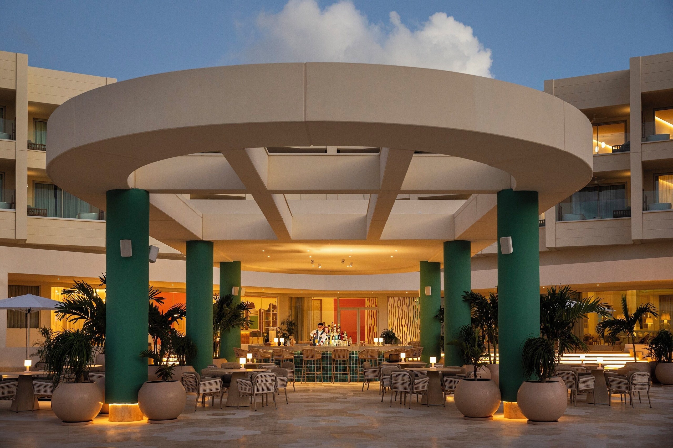 The lobby bar with seating areas and large planters at JOIA Aruba by Iberostar