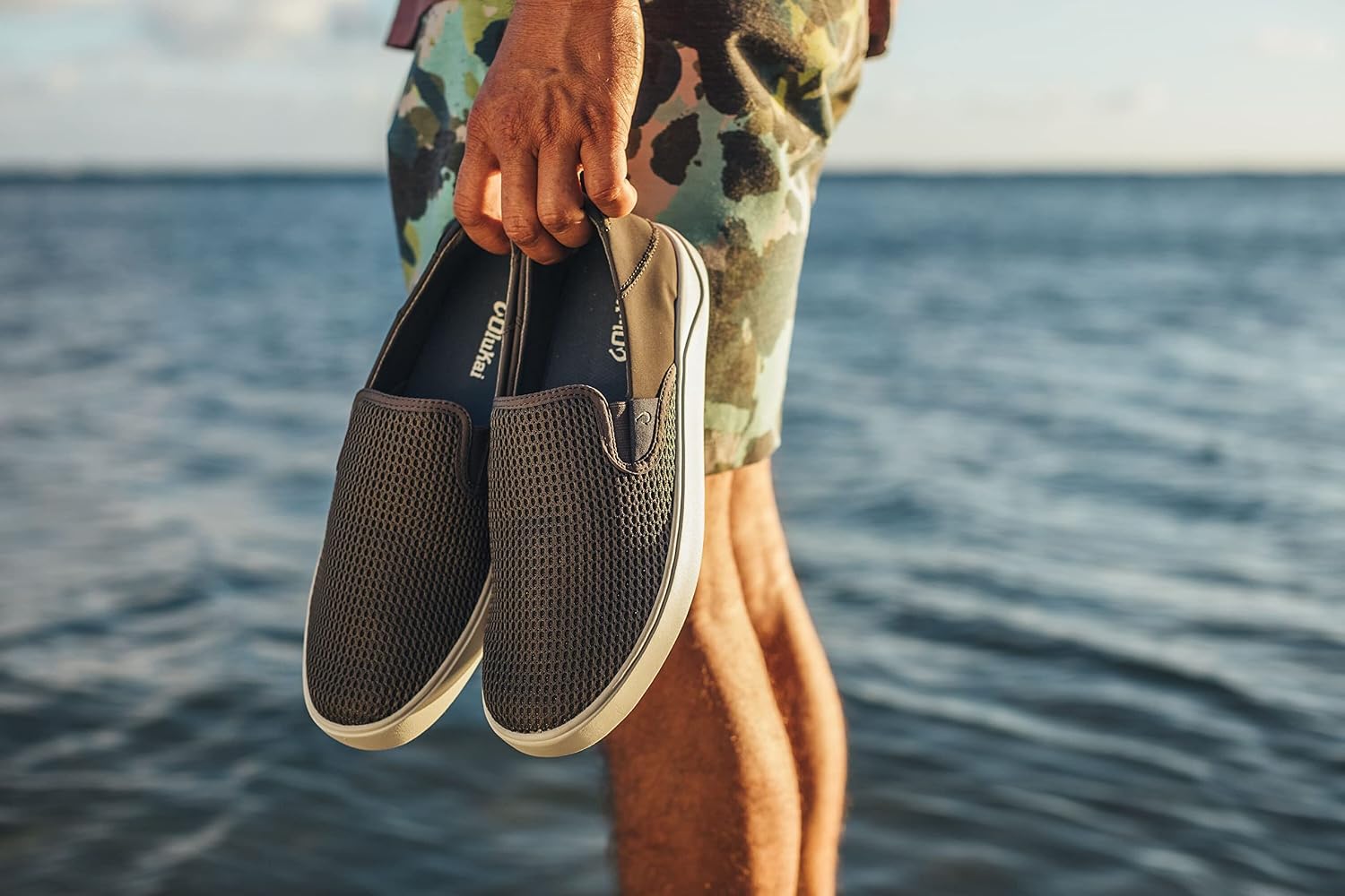 OluKai Lae'ahi slip on shoes carried by the water, worn without socks
