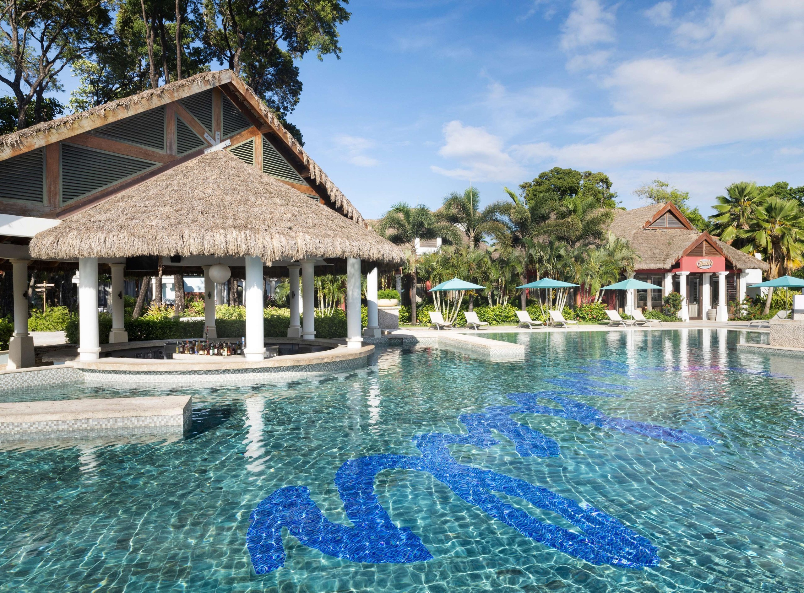 Pool with a thatched swim-up bar and the blue Sandals swan mosaic at Sandals Royal Barbados