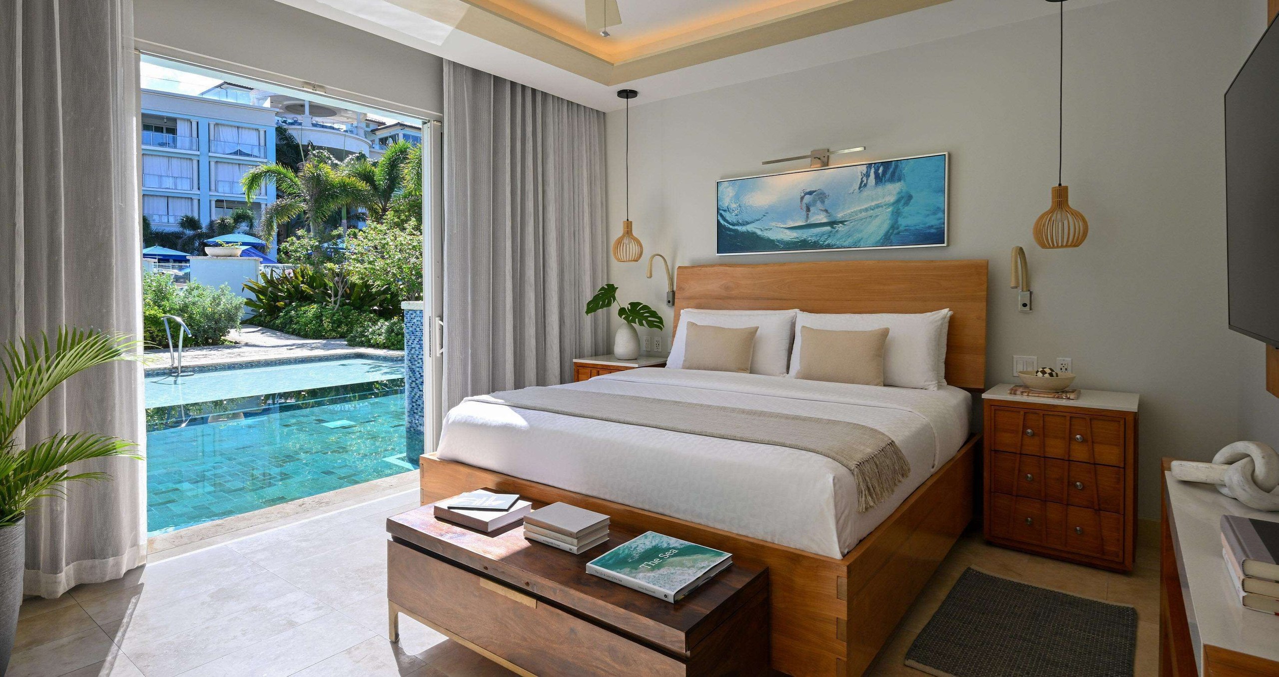 A bright suite bedroom at Sandals Royal Barbados with a platform bed and sliding doors opening to a pool and patio