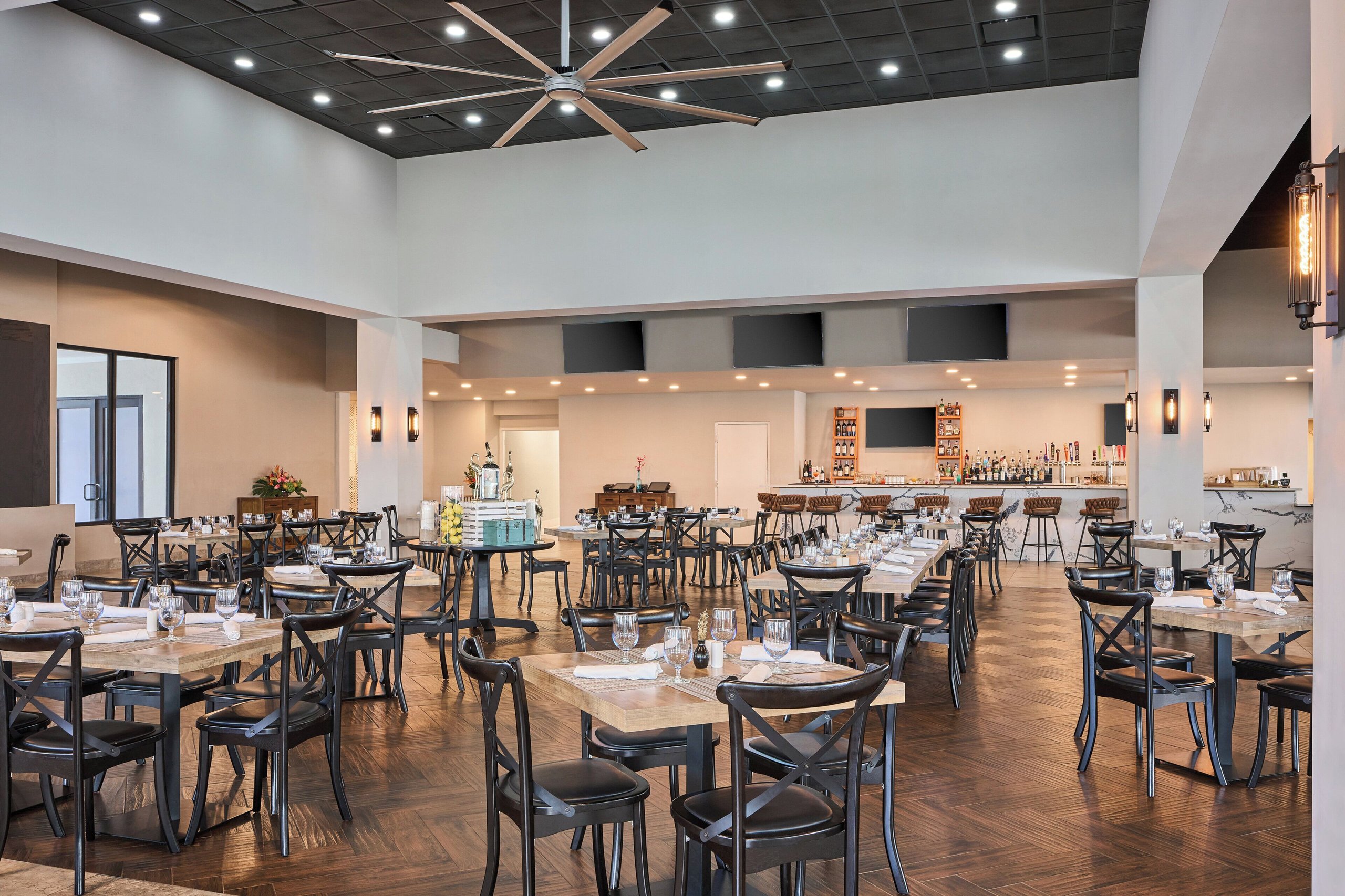 Spacious dining room at voco Sandpiper with wooden tables, a long bar, and warehouse-style lighting