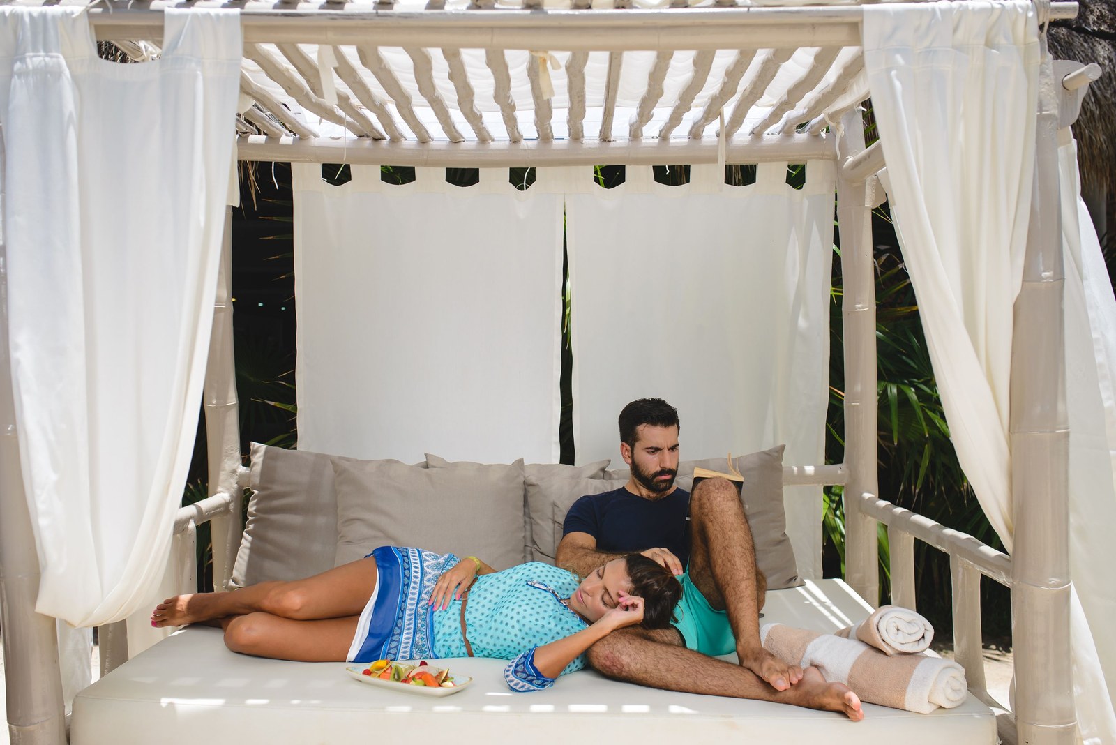 A couple on a white canopied Bali bed in the Pure relaxation area