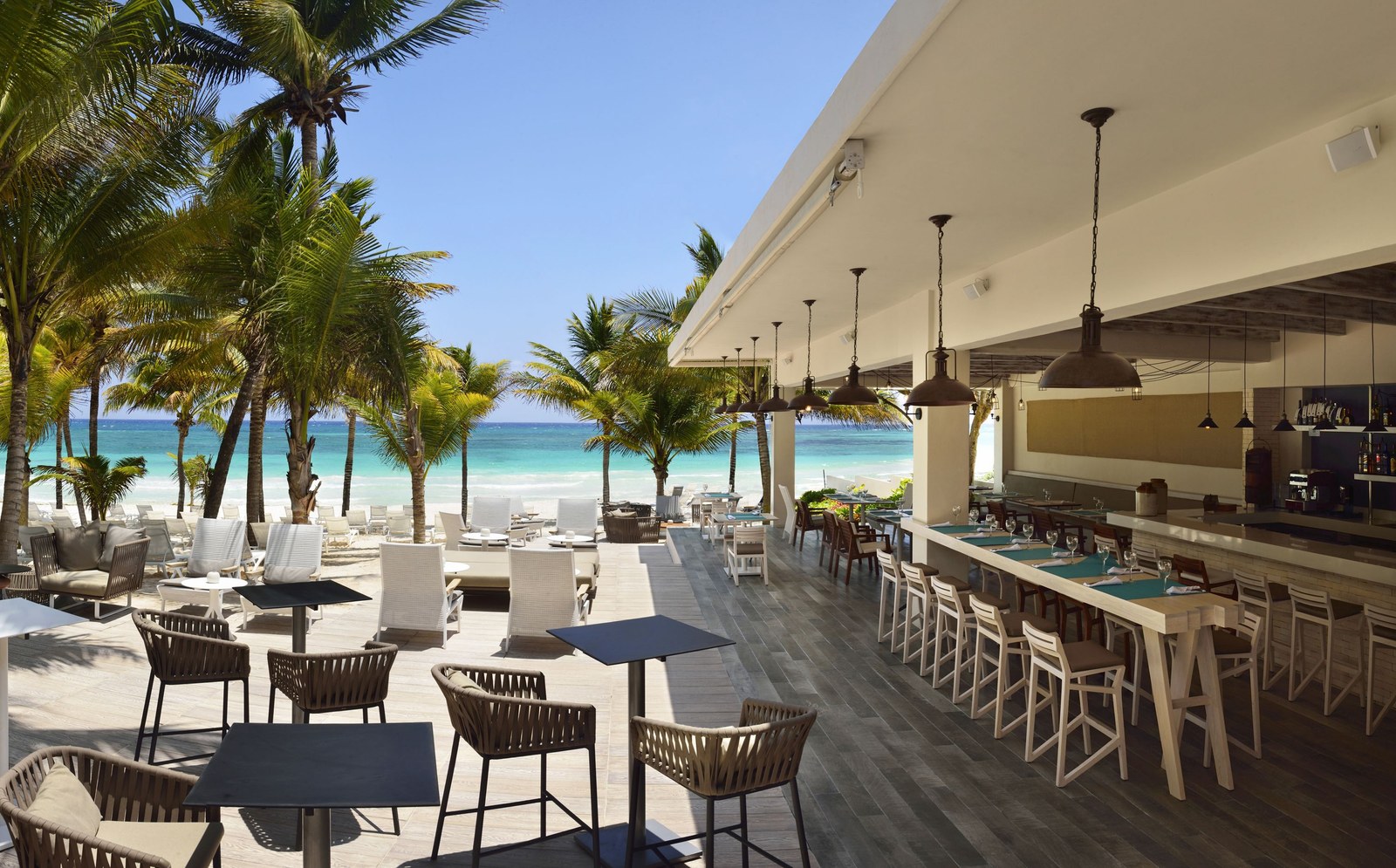 BLoved, the beachside restaurant at Catalonia Royal Tulum, with outdoor tables and a bar facing the sea