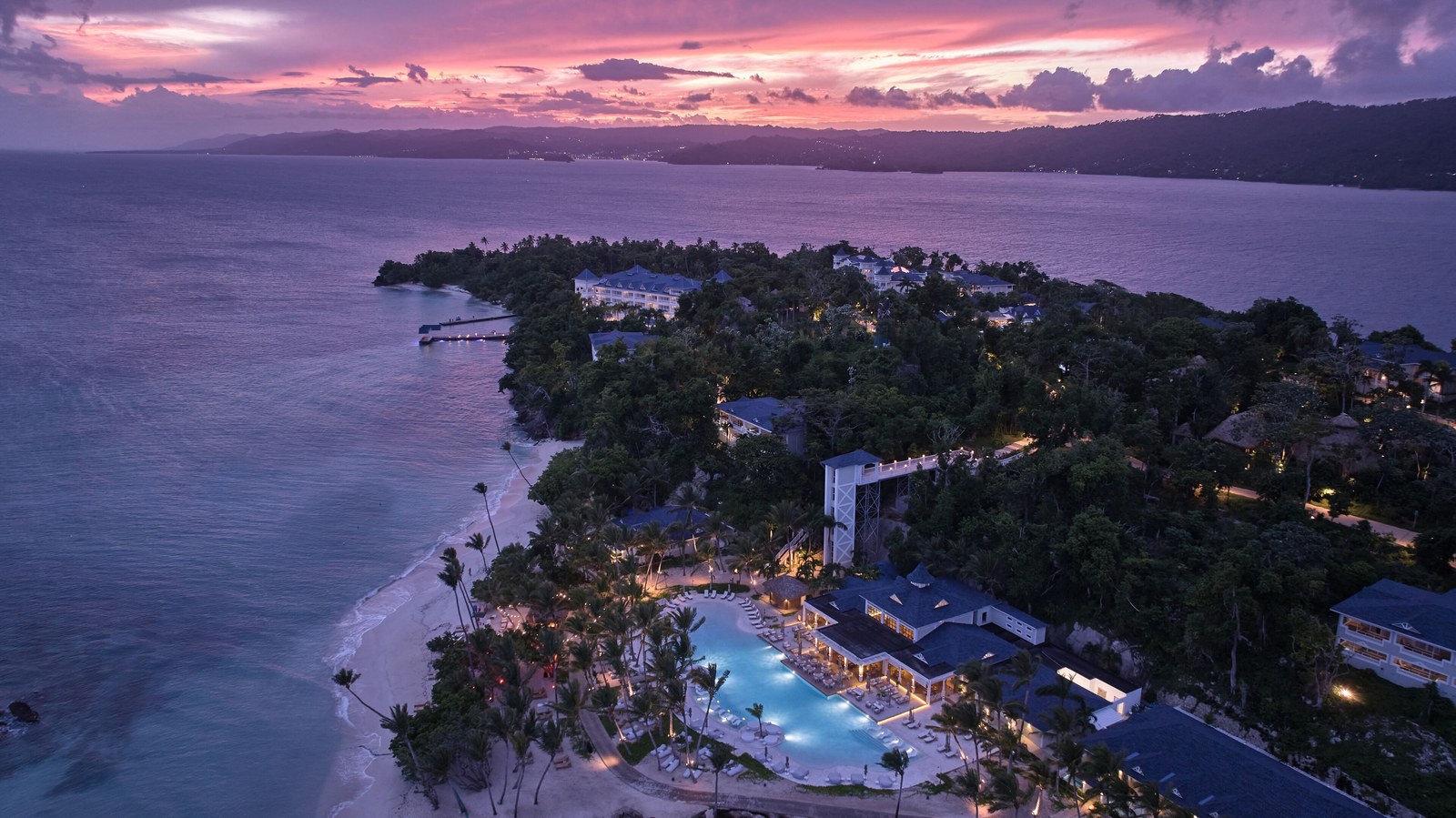 Aerial view of Cayo Levantado Resort at sunset with the pools lit and the bay beyond