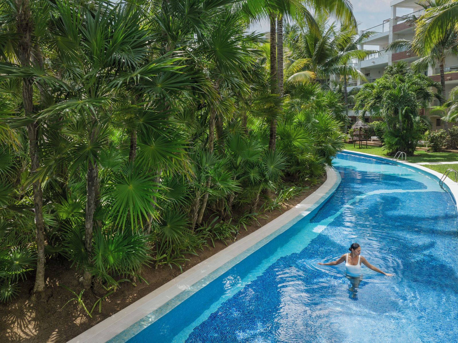 The lazy river winding through the palms at Excellence Playa Mujeres
