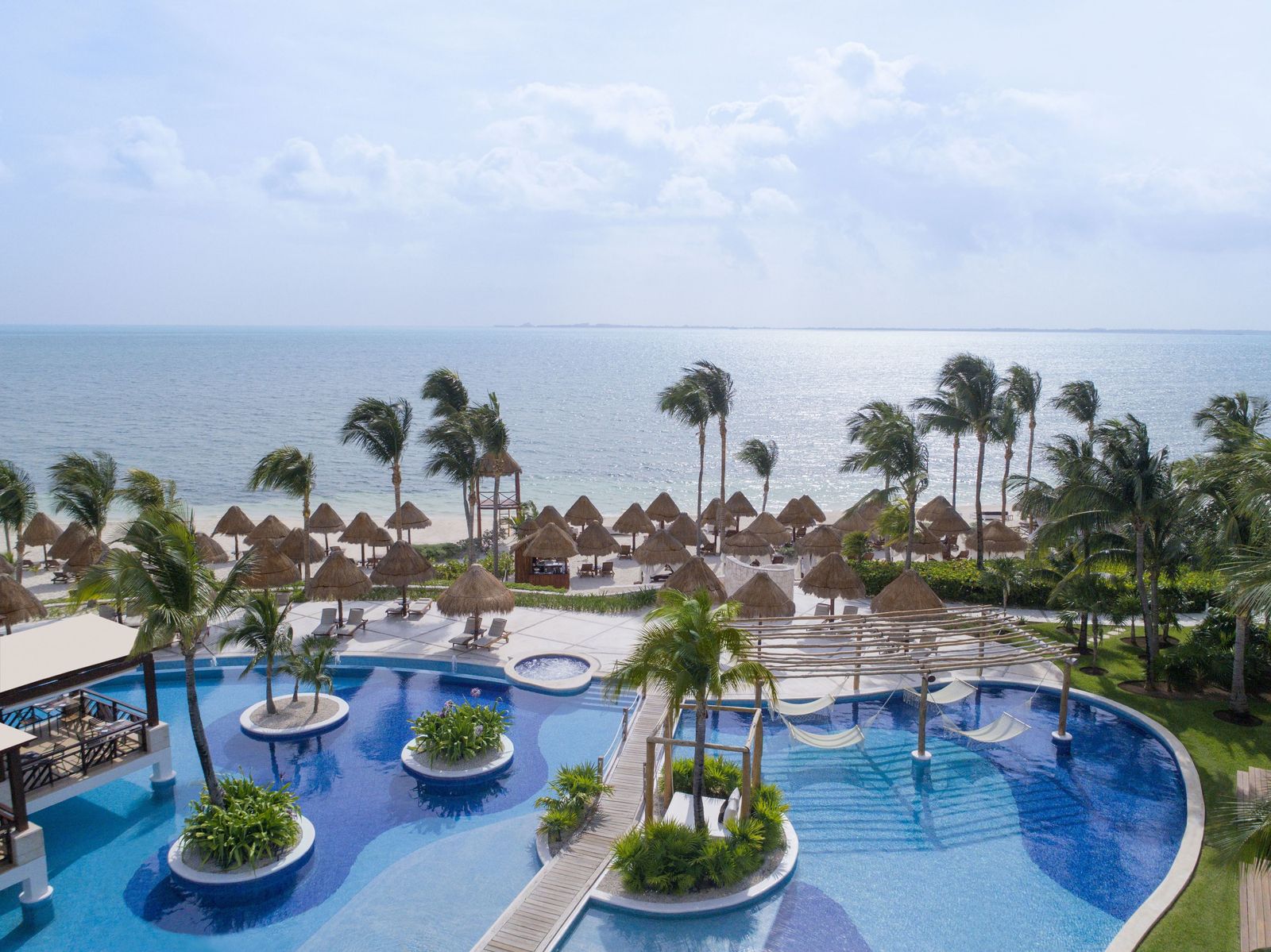 Main pools with in-water hammocks facing the ocean at Excellence Playa Mujeres