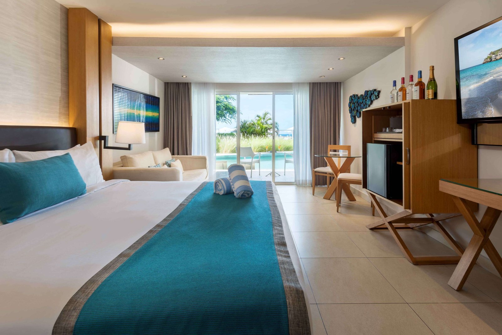 Junior Suite at Sonesta Ocean Point with a king bed, teal runner and the ocean through the balcony doors