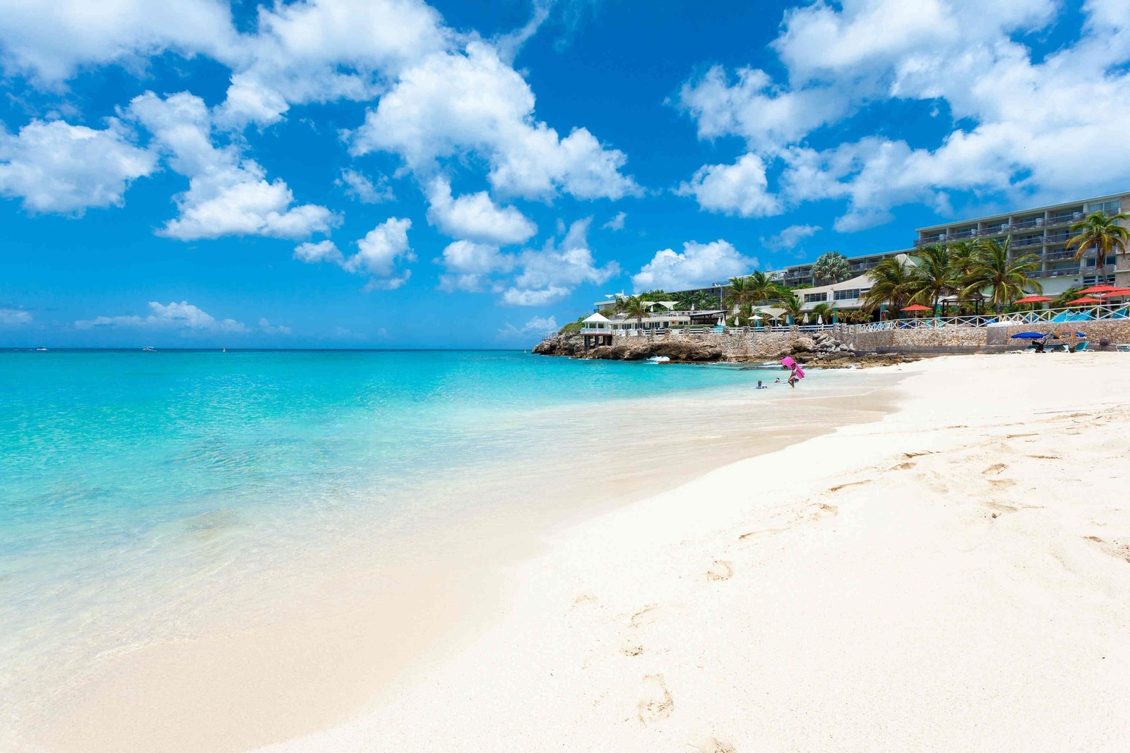 Maho Beach in St. Maarten, white sand and clear water, with Sonesta Ocean Point on the point at the end