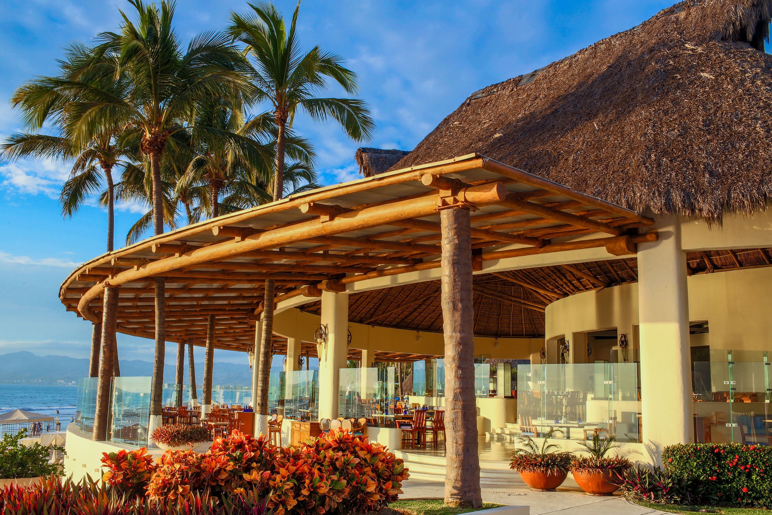 A palm-roofed open-air dining area at Grand Velas Riviera Nayarit looking out over the ocean